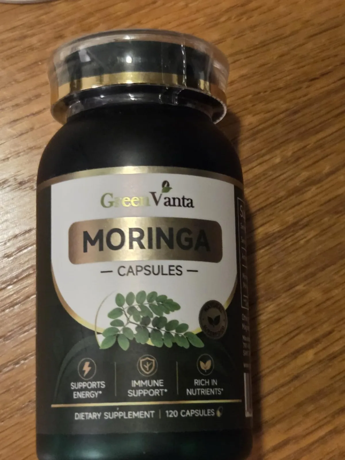 GREENVANTA Moringa Capsules bottle standing on a wooden table